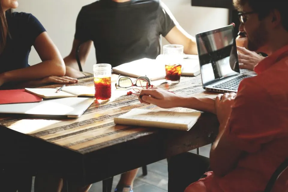 People working together around a table with laptops and notes.